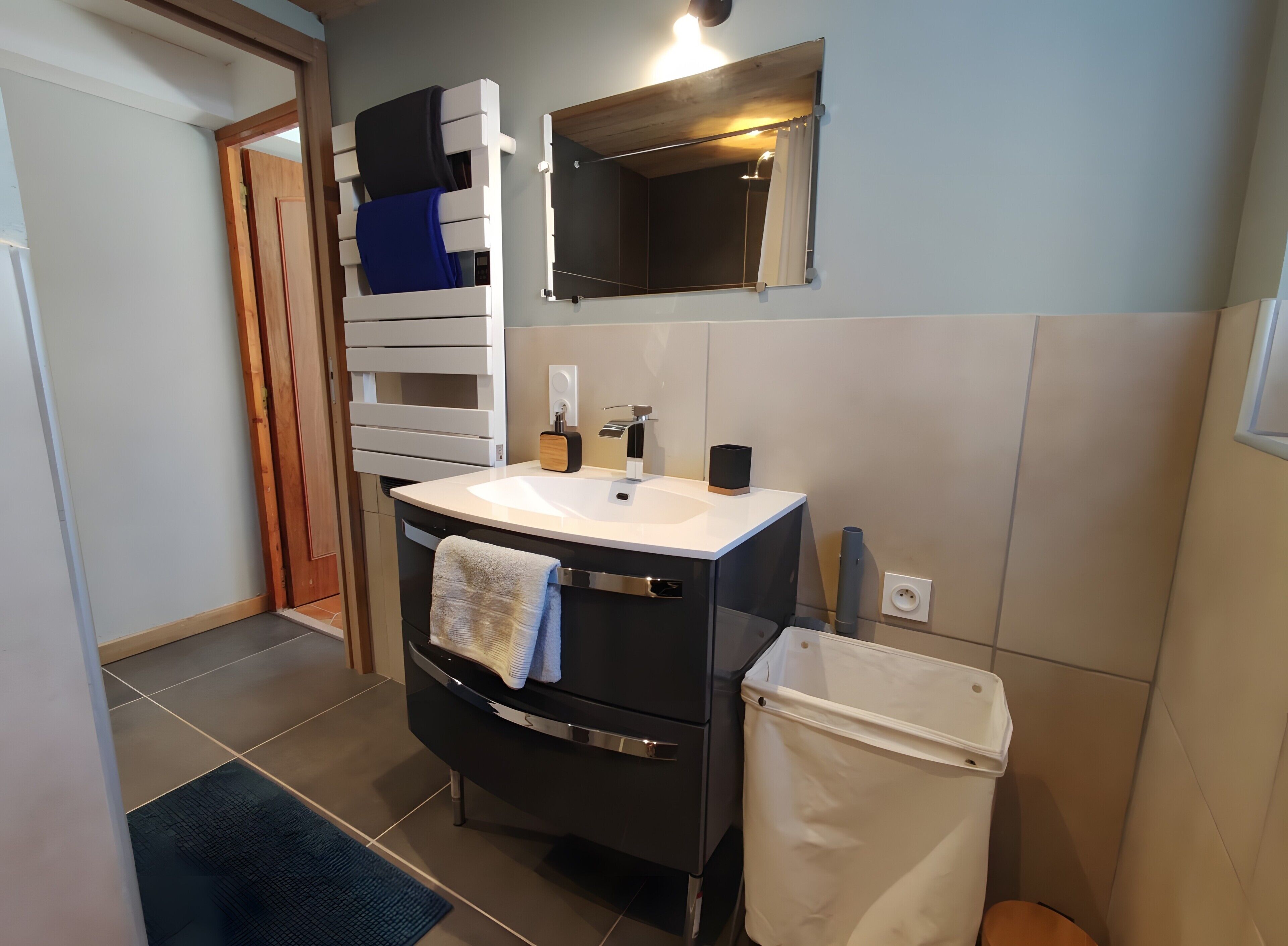 A modern bathroom with a white sink, black cabinet, and a mirror above.