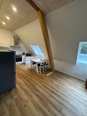 Moderni keittiö, jossa on ruokailutila, puupalkit ja kattoikkunat.