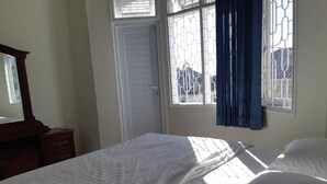 Une chambre à coucher avec un lit, une commode et une fenêtre avec des rideaux.