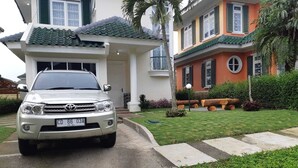 Une Toyota argentée était garée devant une maison dont le toit était recouvert de tuiles et dont la pelouse était bien entretenue.