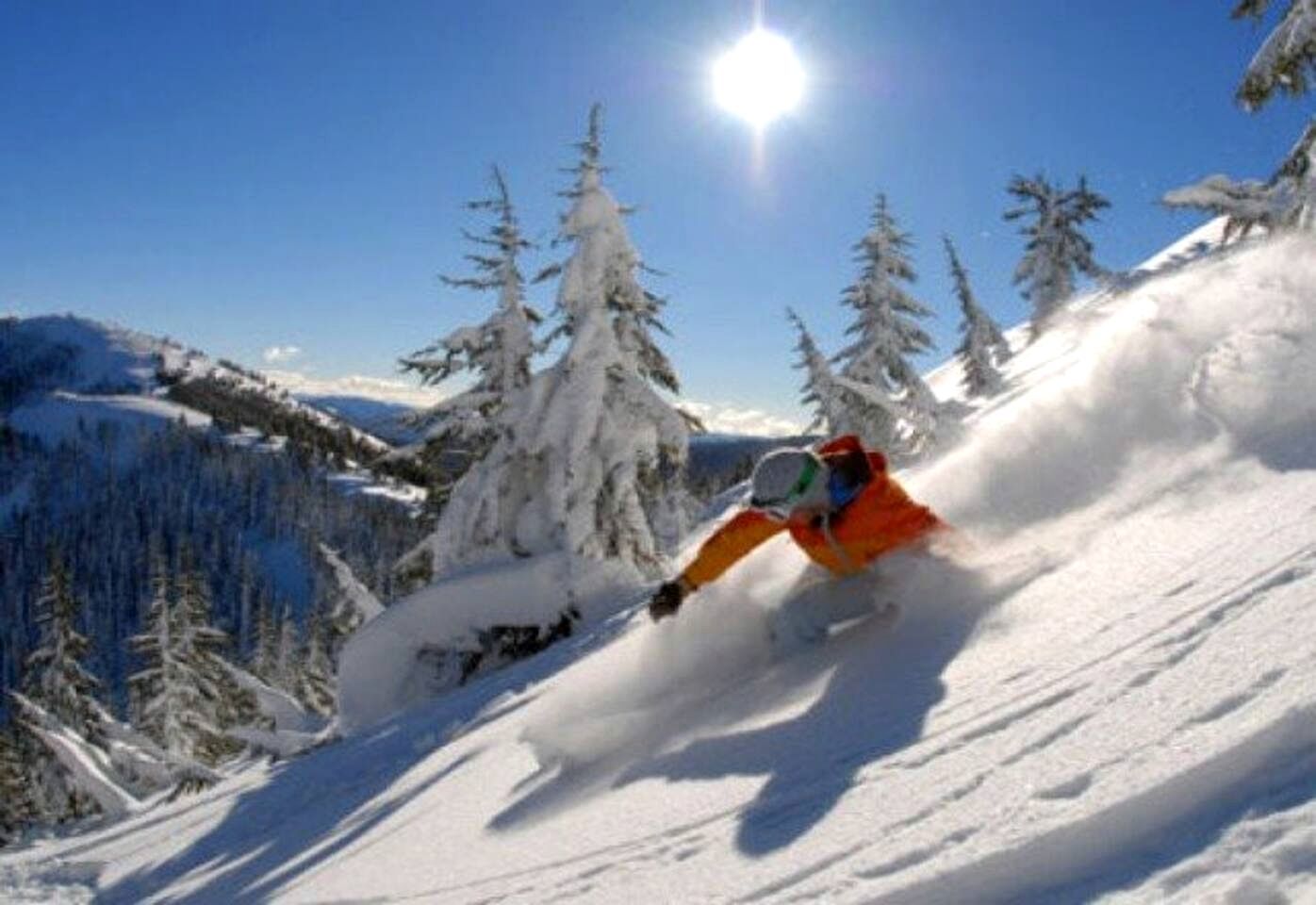 A snowy mountain landscape with a skier in motion.