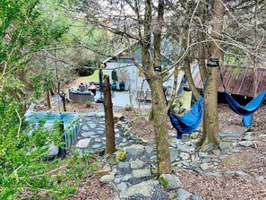 A rustic outdoor setting with a hammock, a shed, and a garden area with rocks and plants. - Peaceful Cottage with Hot-tub in Fleetwood, North Carolina (Fleetwood)