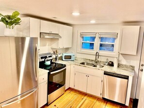 A compact kitchen with stainless steel appliances, a microwave, and a dishwasher.