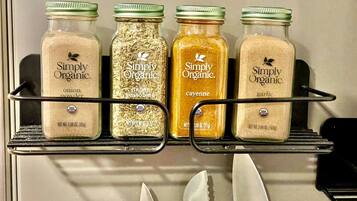 Quatre pots d’épices de la marque Simply Organic, rangés sur une étagère dans la cuisine.