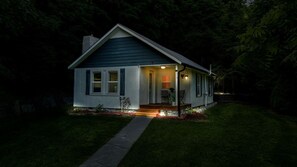 Una casa con porche delantero, un camino que lleva a la entrada y un pequeño jardín con flores.