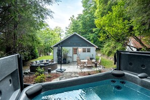 Een achtertuin met een jacuzzi, buitenmeubilair en een tuinhuisje.