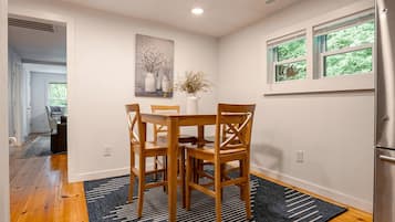 A dining area with a wooden table and chairs, a vase with flowers, and a painting on the wall.