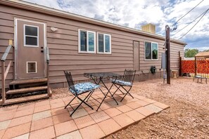 Einbungalow mit Haustür, zwei Fenstern und einer Terrasse mit Tisch und Stühlen.