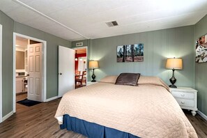 Ein Schlafzimmer mit einem Bett, Nachttischen, einer Tür zu einem Badezimmer und einem Bild an der Wand.