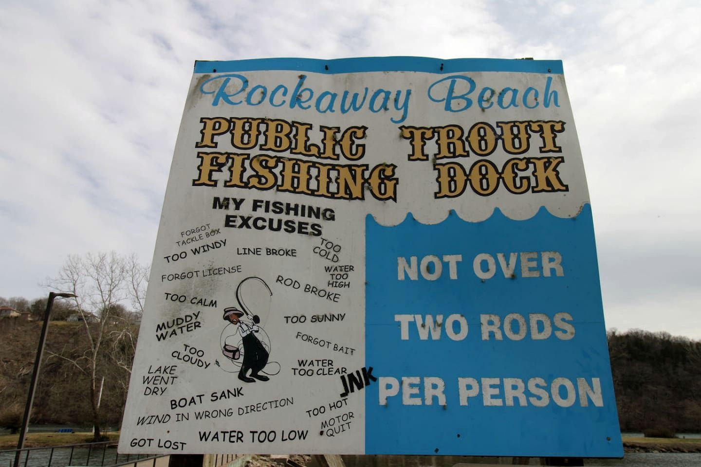 Bordje voor de Rockaway Beach Public Trout Fishing Dock met een lijst van excuses voor het vissen en een regel: maximaal twee hengels per persoon.
