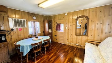 A wooden-paneled room with a dining table, chairs, a sofa, and a mirror.