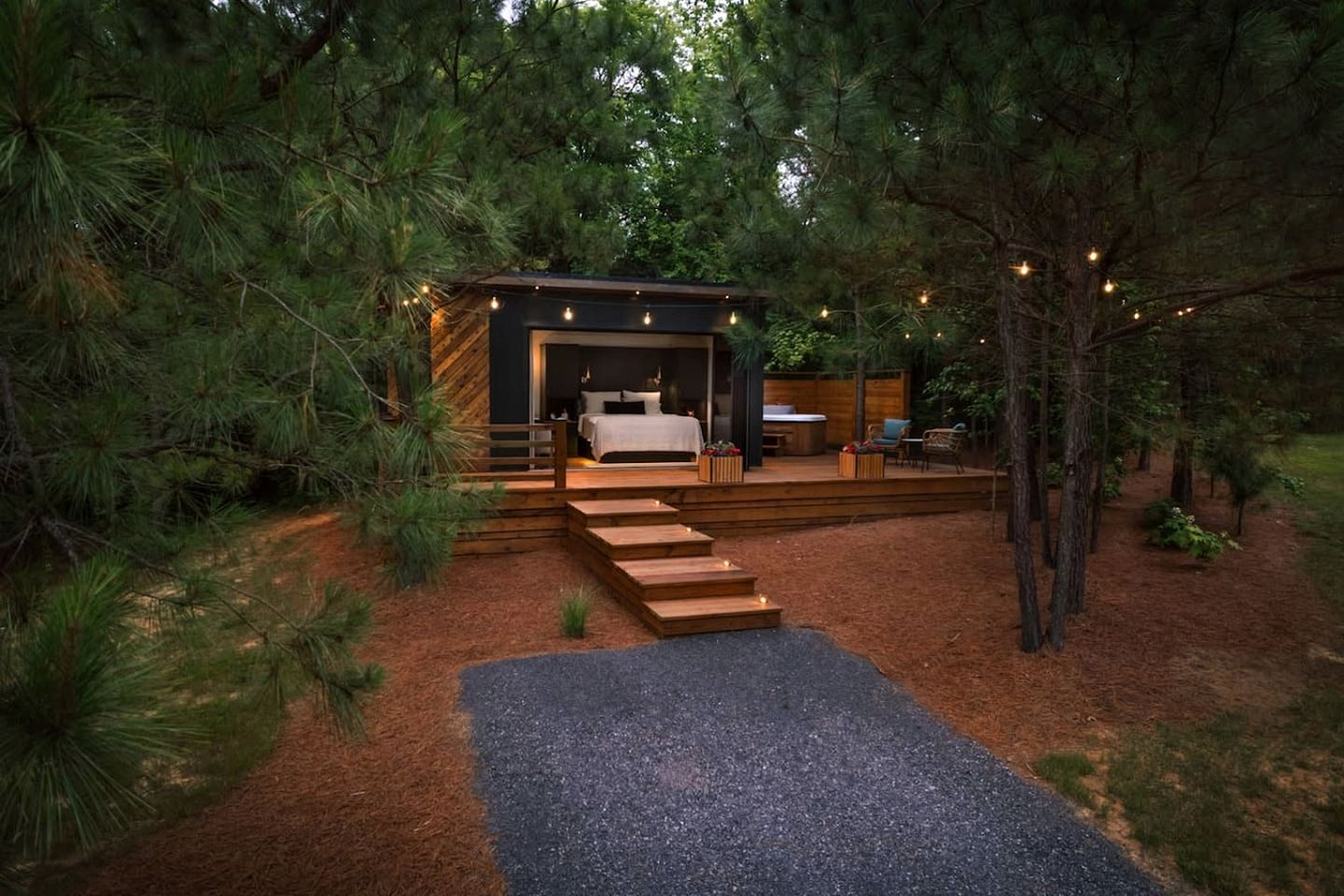 Une cabane moderne dotée d’une chambre, d’un espace salon extérieur et d’un escalier menant à l’entrée.
