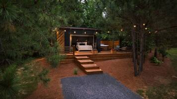 Une cabane moderne dotée d’une chambre, d’un espace salon extérieur et d’un escalier menant à l’entrée.