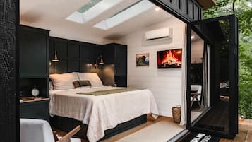 Een slaapkamer met een bed, nachtkastjes, een airconditioning, een open haard en uitzicht op de omgeving.