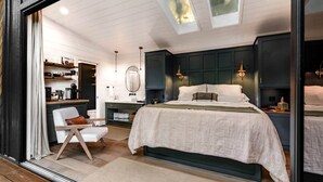 Quarto com cama, mesas de cabeceira, escrivaninha e uma cadeira.