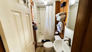 Un baño pequeño con inodoro, lavamanos, ducha y toallero.
