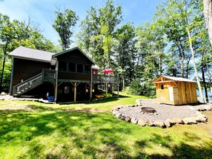 A cabin with a deck, a small shed, and a fire pit area. - Pet-Friendly Lakeside Cabin Ideal for a Family Getaway in Wisconsin (Stone Lake)