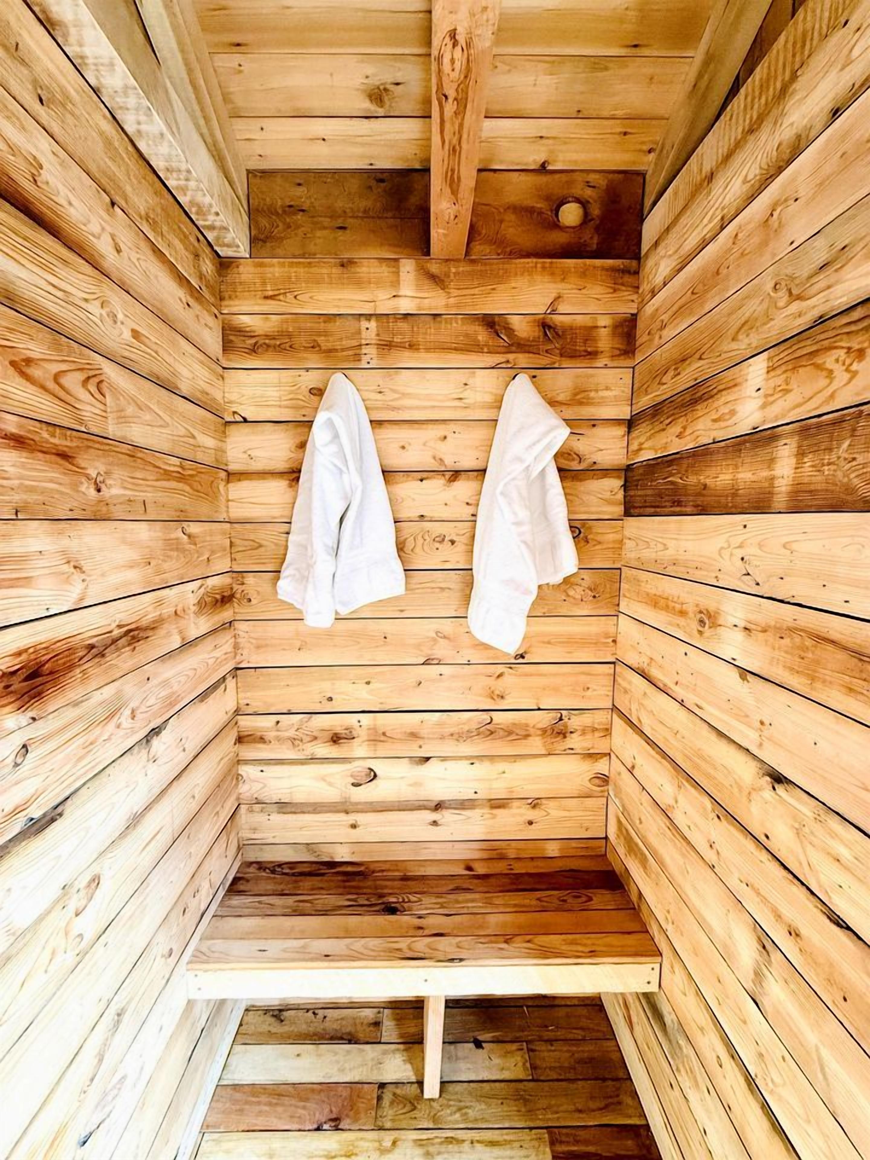 Una sauna de madera con bancos y toallas colgadas en la pared.