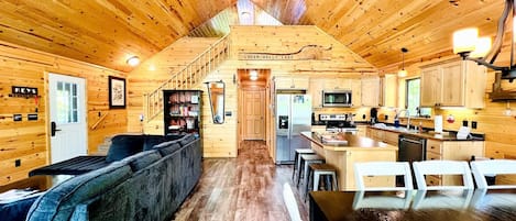 Interior de una cabaña de madera con sala de estar, cocina y comedor.