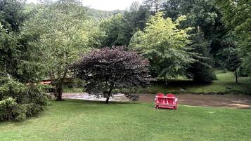 Un parc avec une chaise Adirondack rouge, un étang et de nombreux arbres.