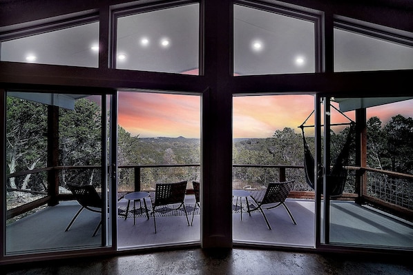 Ein Zimmer mit großen Fenstern, einem Balkon mit Sitzgelegenheiten und Blick auf die Landschaft.