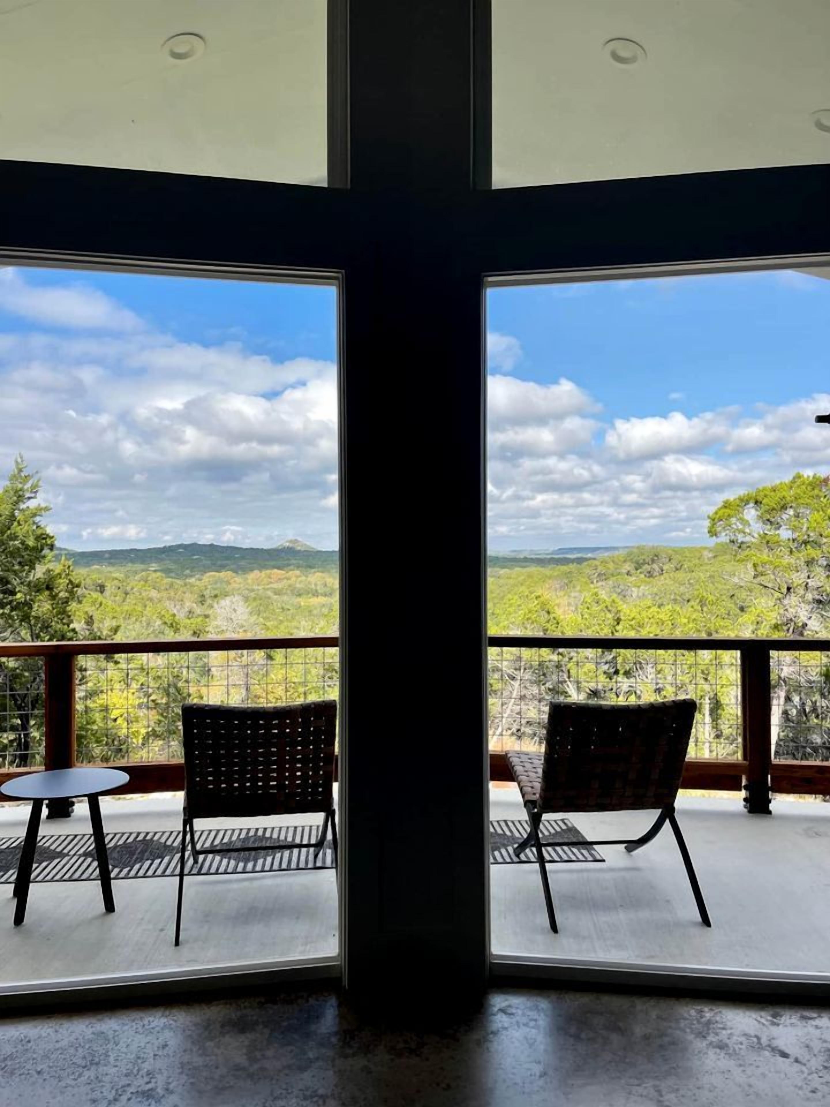 Ein Balkon mit zwei Stühlen und einem kleinen Tisch, mit Blick auf eine Berglandschaft.