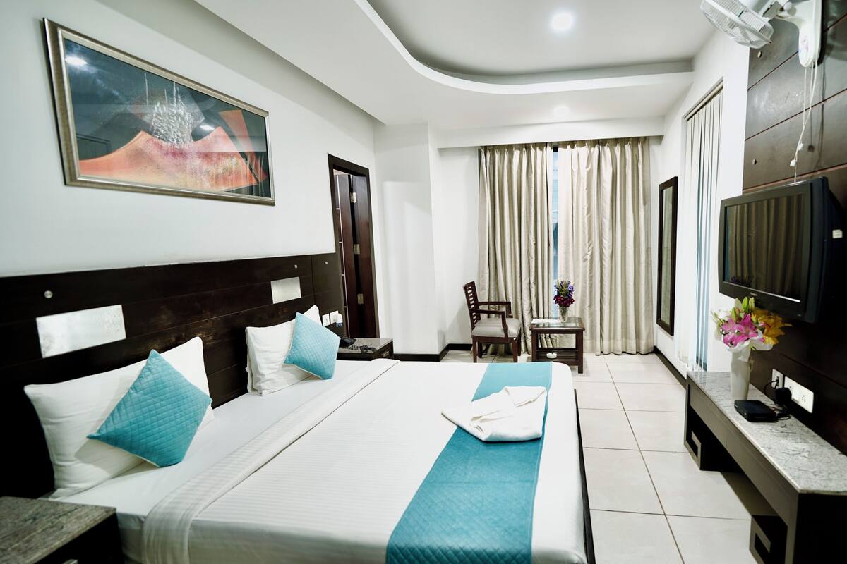 Una habitación de hotel con una cama, televisor, escritorio y una silla.