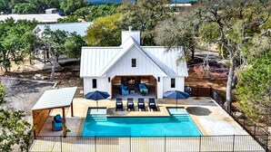 Una casa grande con piscina, mobiliario de exterior y vistas del paisaje circundante.