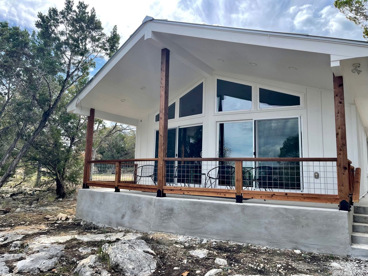 A modern house with a covered porch, large windows, and a concrete foundation.