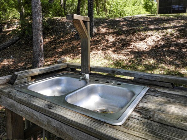 A rustic wooden picnic table with a metal sink.