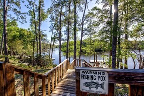 A wooden dock leading to a lake with a warning sign about a fishing pox. - Cabin Getaway: Pet-Friendly Oasis on the Ochlockonee River Bend, Ideal for Fishing and Swimming (Wakulla County)