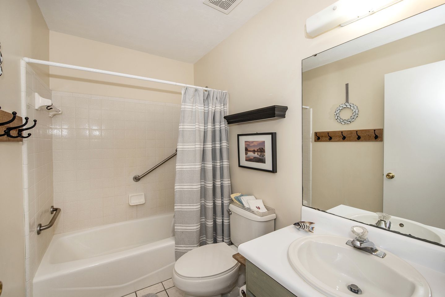 Une salle de bain équipée d’une baignoire, de toilettes et d’un lavabo, ainsi que d’une barre d’appui et d’un rideau de douche.