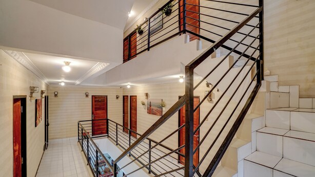Un interior de varios niveles con una escalera, paredes de azulejos blancos y puertas de madera.