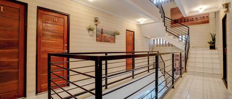Un vestíbulo de hotel con una escalera, puertas de madera y una pared decorativa.