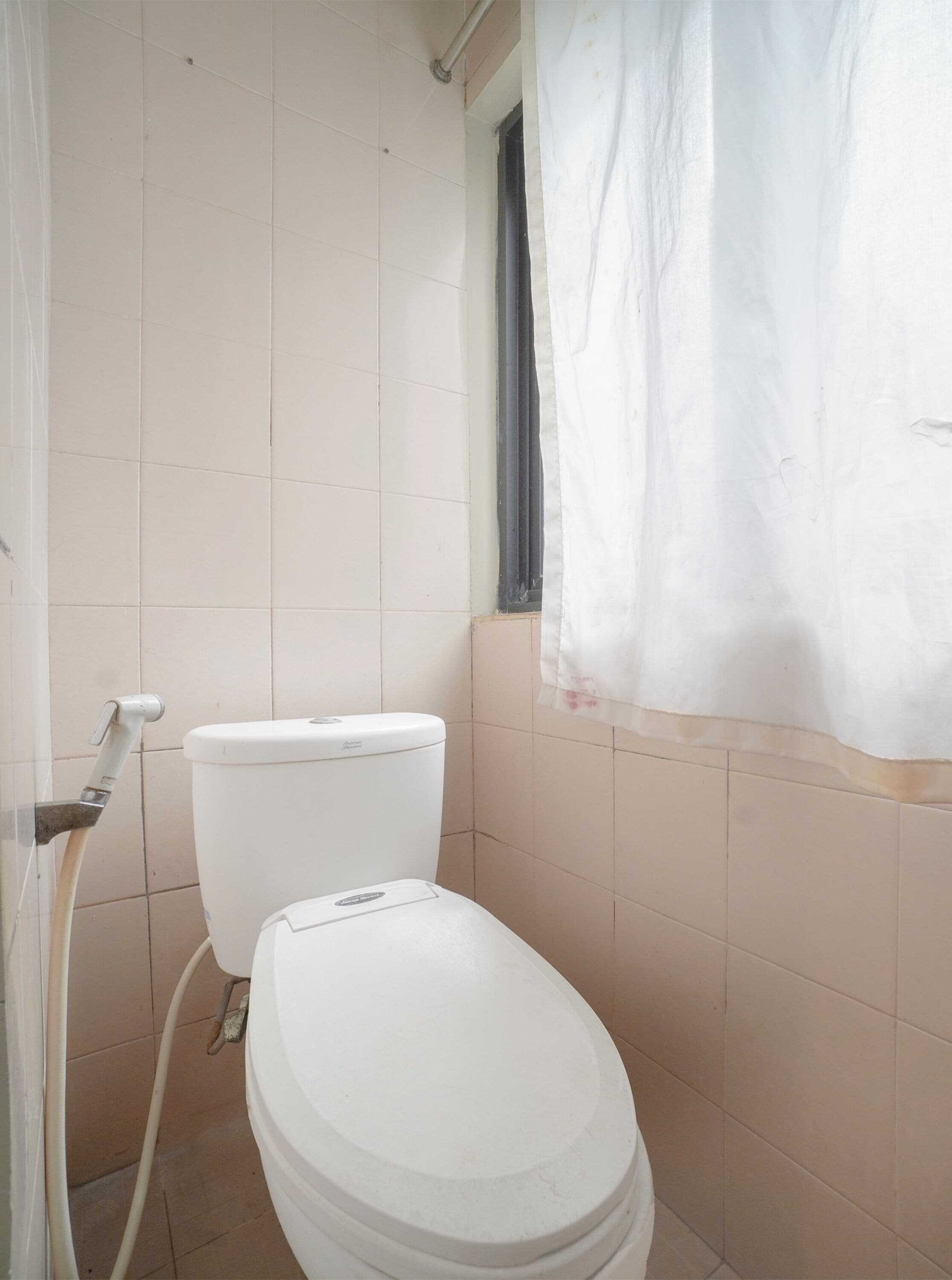 A bathroom with a toilet, a shower curtain, and tiled walls.