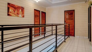 Un vestíbulo de hotel con una escalera, puertas de madera y un cuadro en la pared.
