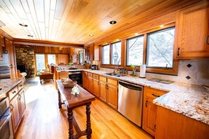 A spacious kitchen with wooden cabinets, a granite countertop, and a built-in dishwasher. - Luxury Cottage Ranch with Hot-Tub, Theater and Pool Table in Watauga County, North Carolina (Sugar Grove)