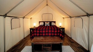 A tent with a bed, two bedside lamps, and a wooden bench. - Build Amazing New Memories at this Lovely Safari Tent in Branson, Missouri (Branson)