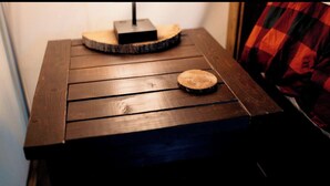 A wooden table with a small round wooden object on top, a black electronic device, and a plaid fabric partially visible. - Build Amazing New Memories at this Lovely Safari Tent in Branson, Missouri (Branson)