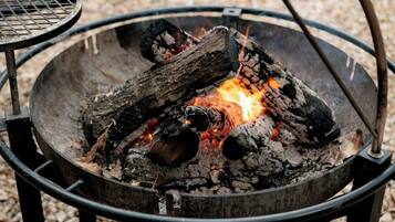 A circular metal fire pit with burning wood and embers.