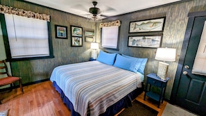Une chambre à coucher comprenant un lit, deux tables de chevet, une chaise, une porte et des éléments de décoration murale.