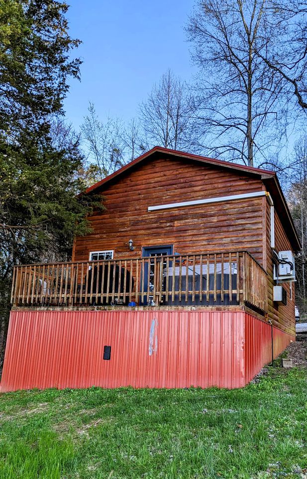 A wooden cabin with a red exterior, a balcony, and a small porch area.