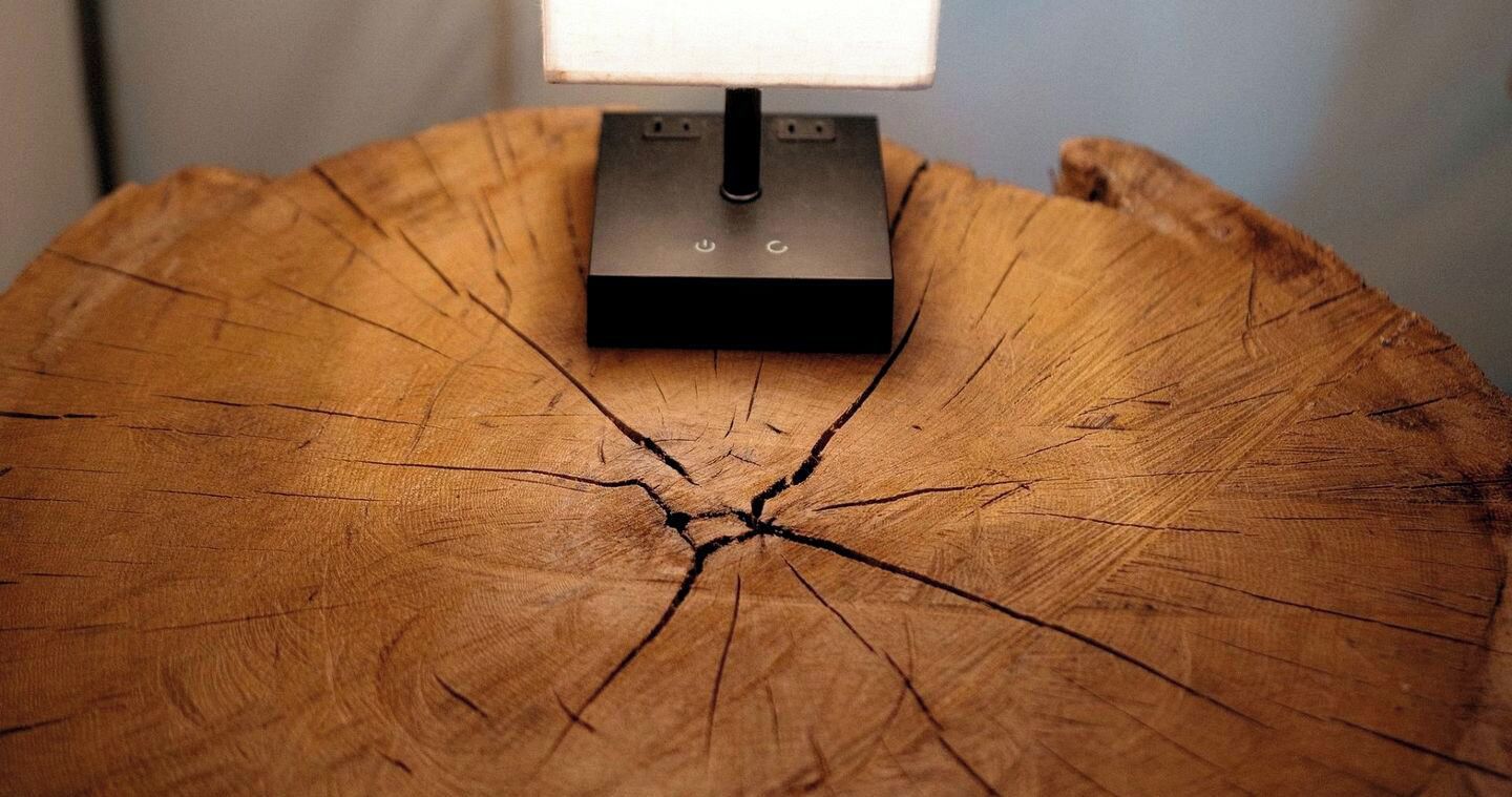 A table with a lamp on a wooden surface.