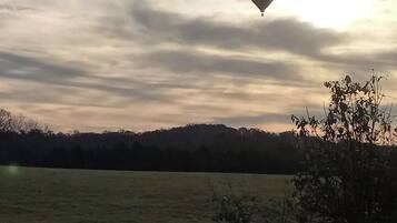 Un paisaje con un campo y árboles a lo lejos bajo un cielo nublado.