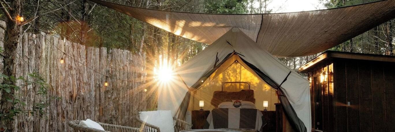 A tent with a bed inside, surrounded by a wooden fence and a canopy.
