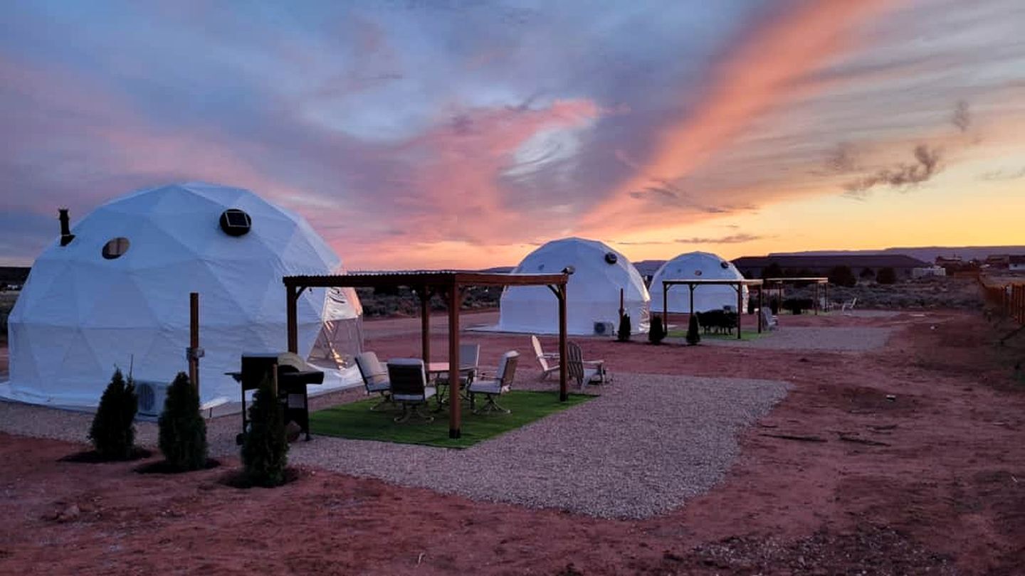 Three dome-shaped yurts with a covered seating area in between.