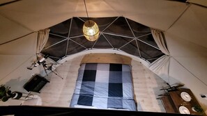 A tent with a checkered floor, a hanging light fixture, and a table with plates. - Charming Dome with Fire Pit and Barbecue in Kanab, Utah (Kanab)