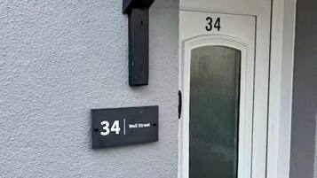 Een witte deur met het nummer 34 en een zwart bordje waarop het adres 34 Well Street staat.