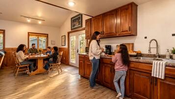 A kitchen with wooden cabinets, a dining area with a table and chairs, and a person standing by the counter.