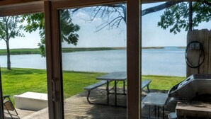 Une terrasse avec des tables de pique-nique et un barbecue, donnant sur un lac.